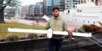 Giorgio holds a drone under construction at OsloMet Oceanlab. We are at the Filipstad harbour in Oslo with boats and buildings in the background.