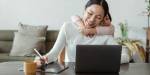 Child hugging mum, who is working on a pc at the kitchen table.