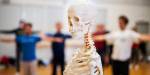 Et skjelett som står foran folk som trener i en gymsal