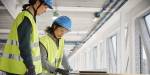 To kvinnelige ingeniører i gul vest ser på en plan