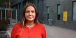 Enisa står i rød genser foran campus på OsloMet
