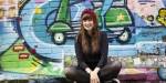 Julia sitting in front of a graffiti art wall.
