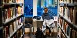 Student sitter og leser på et bibliotek