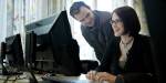 Man and woman working together in front of a computer screen.