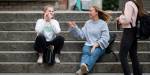 To studenter sitter i trappa på campus og snakker sammen