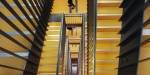 View of yellow stairs and a pair of feet looking down the stair case. Photo: Benjamin A. Ward