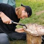 Matthias sits by a game board he's made of wood, burning marks into it with a burner.