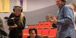 Tre studenter på filmkunst. En av dem filmer og en holder et lite skrin. Alle smiler og ler.