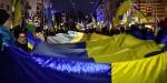 Mange personer med ukrainske flagg i en markering utenfor Russlands ambassade ett år etter Russlands fullskalainvasjon.