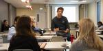 Klasserom med ein workshopleiar og deltakarar som diskuterer.