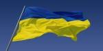 Det ukrainske flagget som vaier i vinden med blå himmel i bakgrunn.