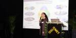 Parisa Gazerani is speaking on stage. A presentation is shown in the background.