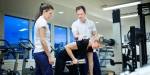Fysioterapistudenter hjelper en pasient i et behandlingsrom med treningsapparater.