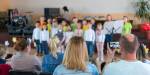 Seen from behind: Parents watching and filming children's choir singing
