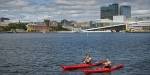 Two kayakers paddling on the Oslo fjord with the Opera House in the background. Photo: Benjamin A. Ward