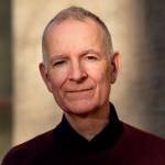 Portrettbilde av Anders Bakken, en mann med grått hår,  tatt i lavt lys utendørs. Foto: Sonja Balci.