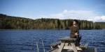 Sheree sitting on a table with Sognsvann bihind her and the dense forest surrounding the lake in the background.