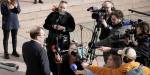 The Norwegian press with cameras and microphones gathered around a politician, asking questions.