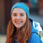 Henriette står på Campus Pilestredet og ikledd turklær og sekk. Hun smiler.