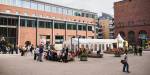 Ein gardsplass mellom murbygningar med eit festivaltelt omringa av barn og vaksne.