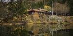 A cabin by the lake surrounded by forest.