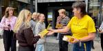 Ein bibliotekar deler ut bøker til studentar på campus.