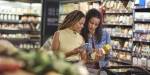 To kvinner ser på matemballasjen på matvarer i butikk.