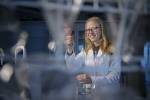 Smilende kvinnelig student i frakk i en lab