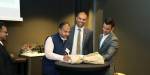 Three people in a group at the signing of the agreement. Carl Thodesen and Arvind Keprate on the right, to the left of them a representative from an Indian university. One person looks on on the left.