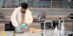 Bildet viser Johar i laboratoriefrakk, vernebriller og hansker i laboratoriet. Han knar hamp i en bolle for å forberede produksjonen.