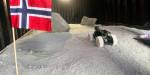 Roboten på plass i et månelignende landskap montert på et bord. Norsk flagg i framgrunnen.