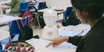 A small robot sits on a desk in class in a primary school.