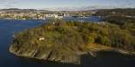 Drone photo of a green island in the Oslo Fjord with the city in the background.