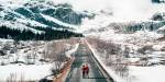 Illustrasjonsfoto: To personer står midt på en langstrakt, tom vei i et snøkledd fjellandskap