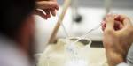 Hender holder to pipetter over et glass i laboratoriet.