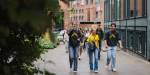 tre glade studenter går sammen på campus under studiestart.
