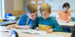 To skoleelever sitter og leser i skolebøker sammen.