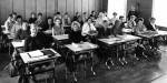 Et eldre sorthvitt-bilde som viser en klasse med kvinnelige studenter ved arbeidspultene sine.