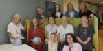 Deler av arbeidsgruppa for barnehagelærarutdanninga sitt jubileum sit og står rundt ein sofa med ballongar