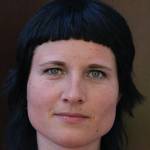 Portrettbilde av NIBR-forsker Mariann Stærkebye Leirvik med svart hår og pannelugg som ser i kamera og smiler.