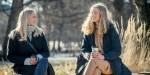 Janne og Matilde sitter på en benk i en park og smiler mot hverandre. Begge har et kaffekrus i hånda.