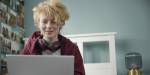 Tenåringsjente med øreklokker sitter foran en pc