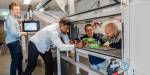 Four students and employees gathered around a task with technical equipment in the wind tunnel.