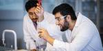 Two men with white coats working in a lab.