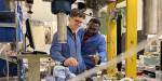 Fredrik and Jacob use technical equipment in the lab. They wear blue coats and collaborate on a task.